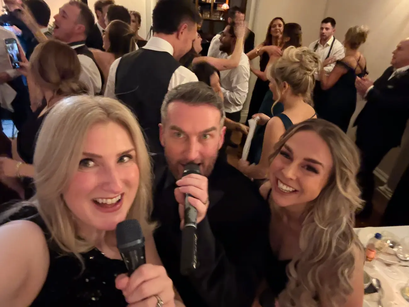 Female surprise wedding singers disguised as waiters performing unexpected entertainment at Glasgow wedding reception